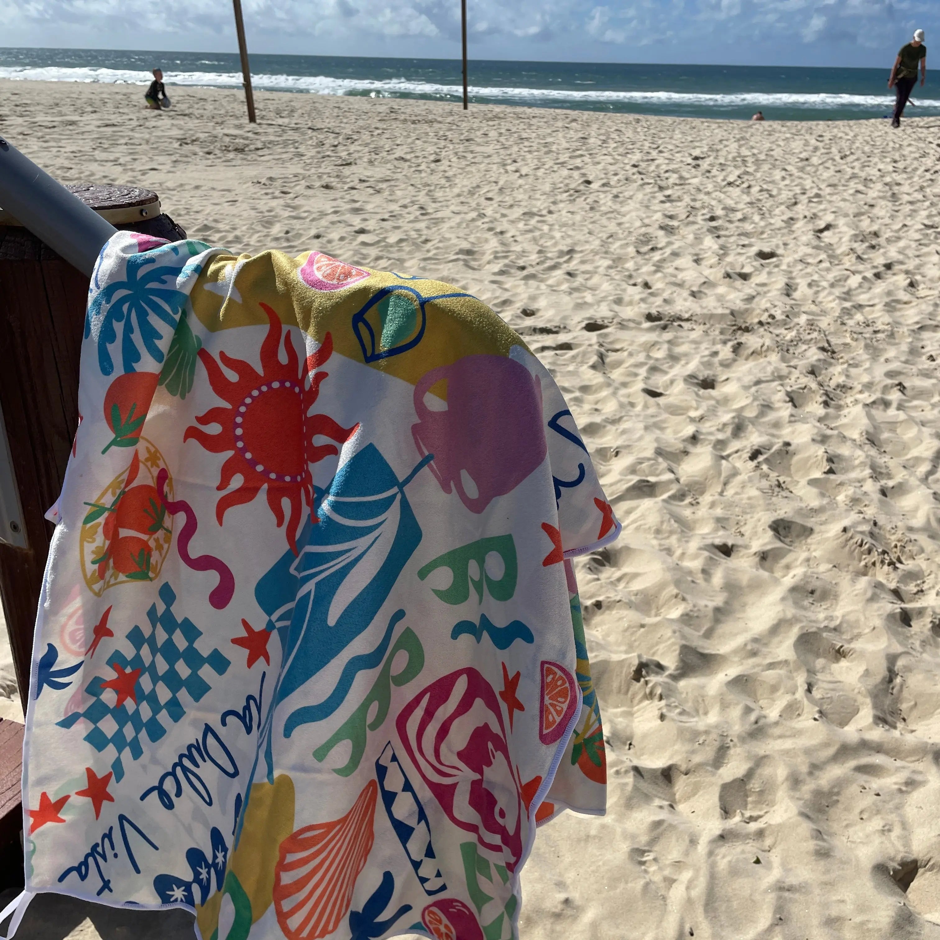 Amalfi coast sand free travel beach towel with pocket hanging on post on beach gold coast