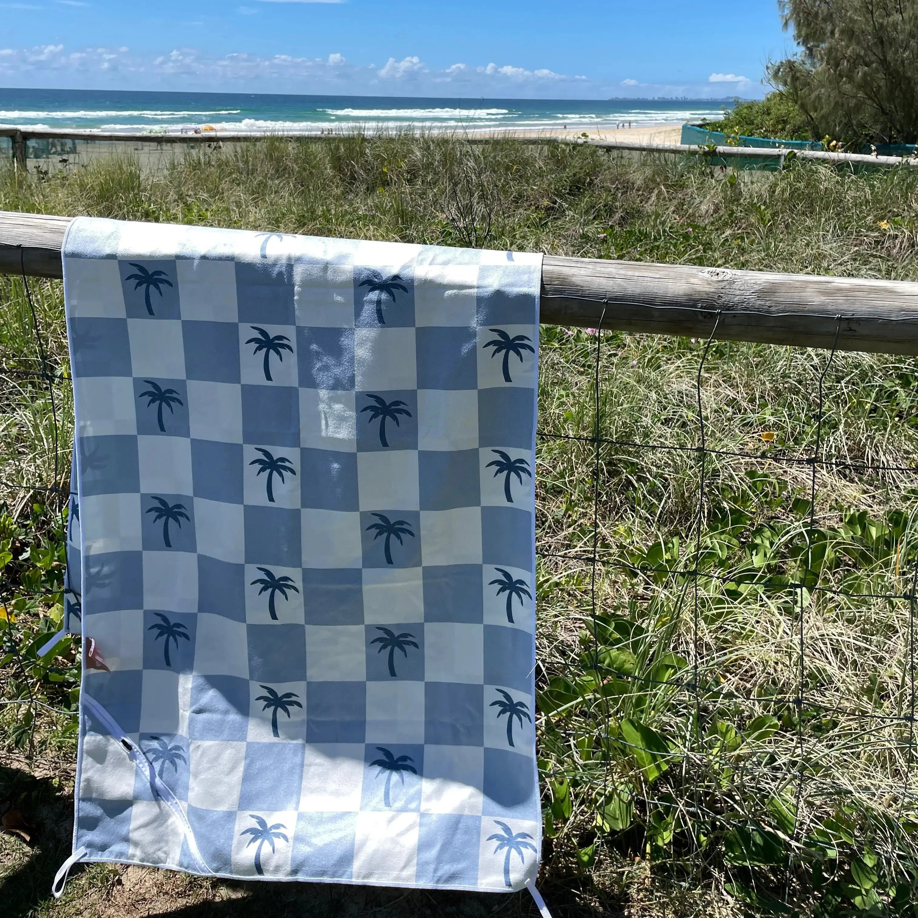 Malibu Blue Checkered sand free Beach Towel With Pocket on white sand beach in Australia