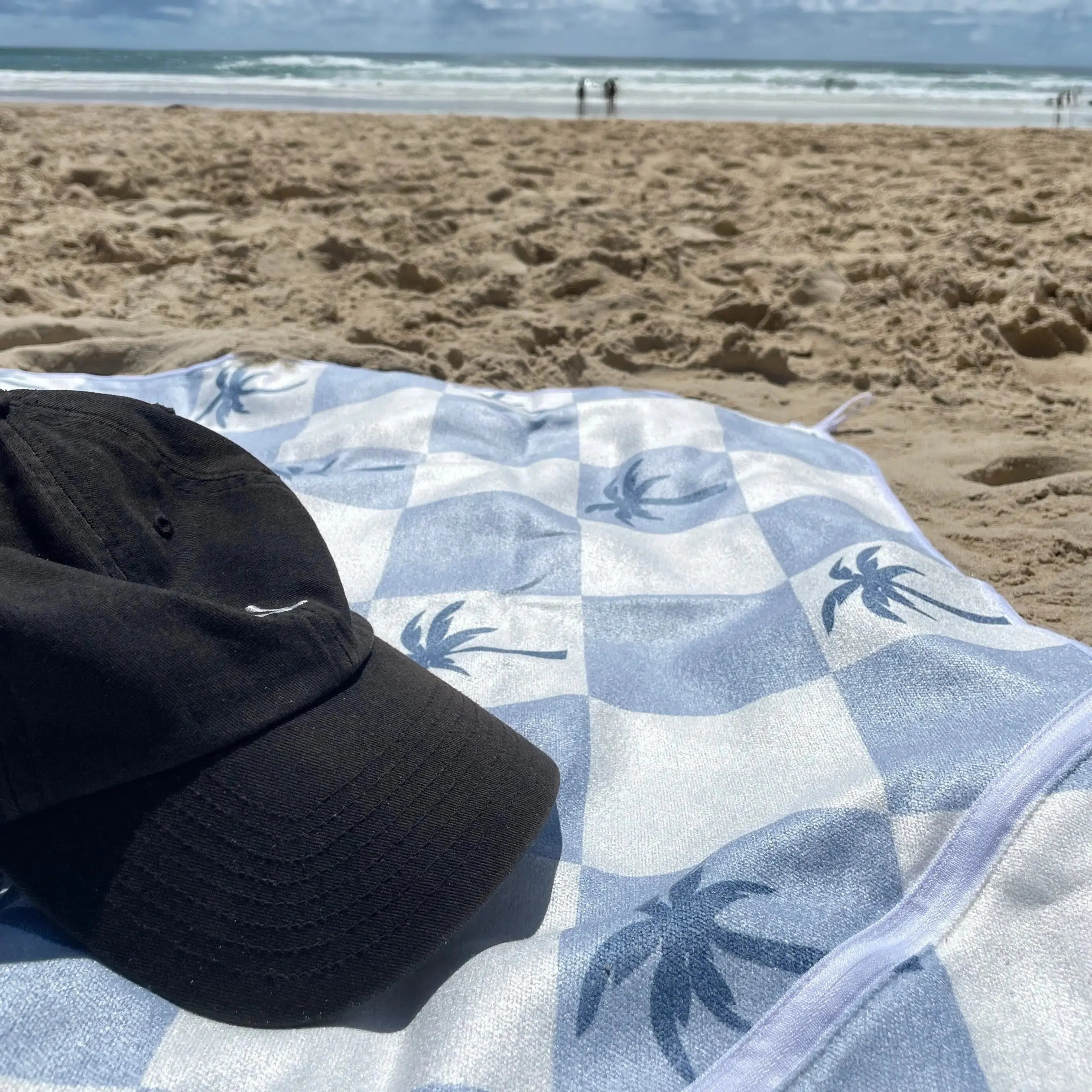 Malibu Blue Checkered sand free Beach Towel With Pocket on white sand beach in Australia