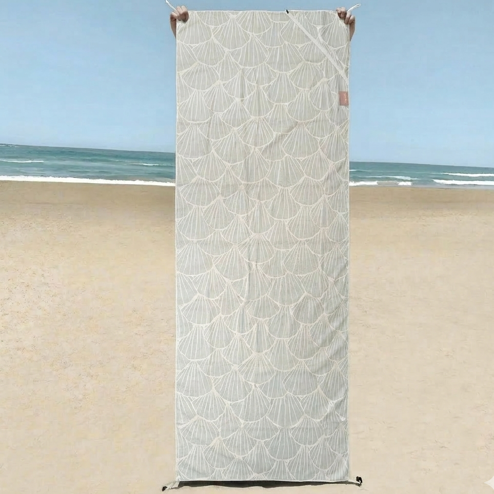 A lightweight sand-free beach towel featuring a soft neutral shell pattern design. Perfect for beach days, travel, or poolside lounging, this quick-dry towel repels sand and folds compactly for easy packing.