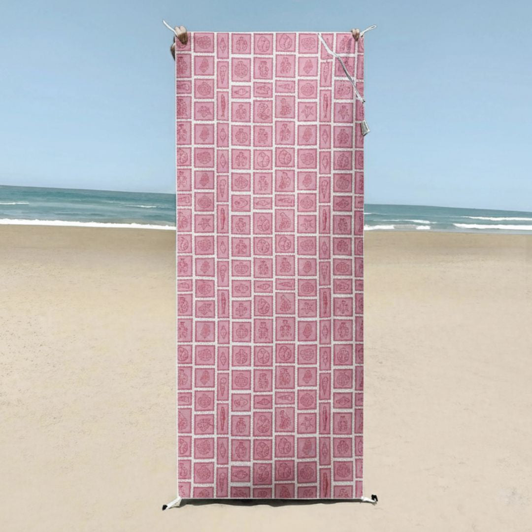 A geometric pattern made up of repeating square tiles in muted pink tones, outlined with lighter lines complementing the serene beach setting