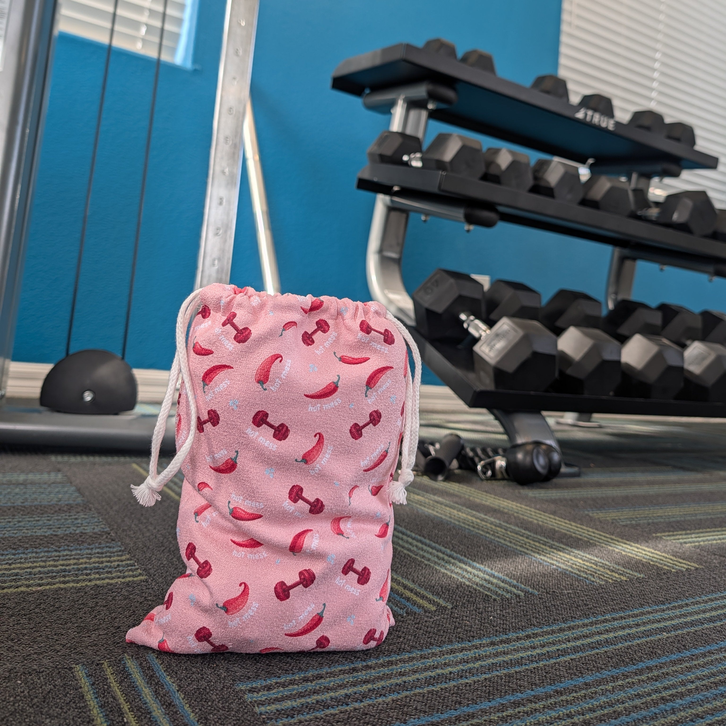 Pink gym towel bag features bold chili peppers and dumbbells.
